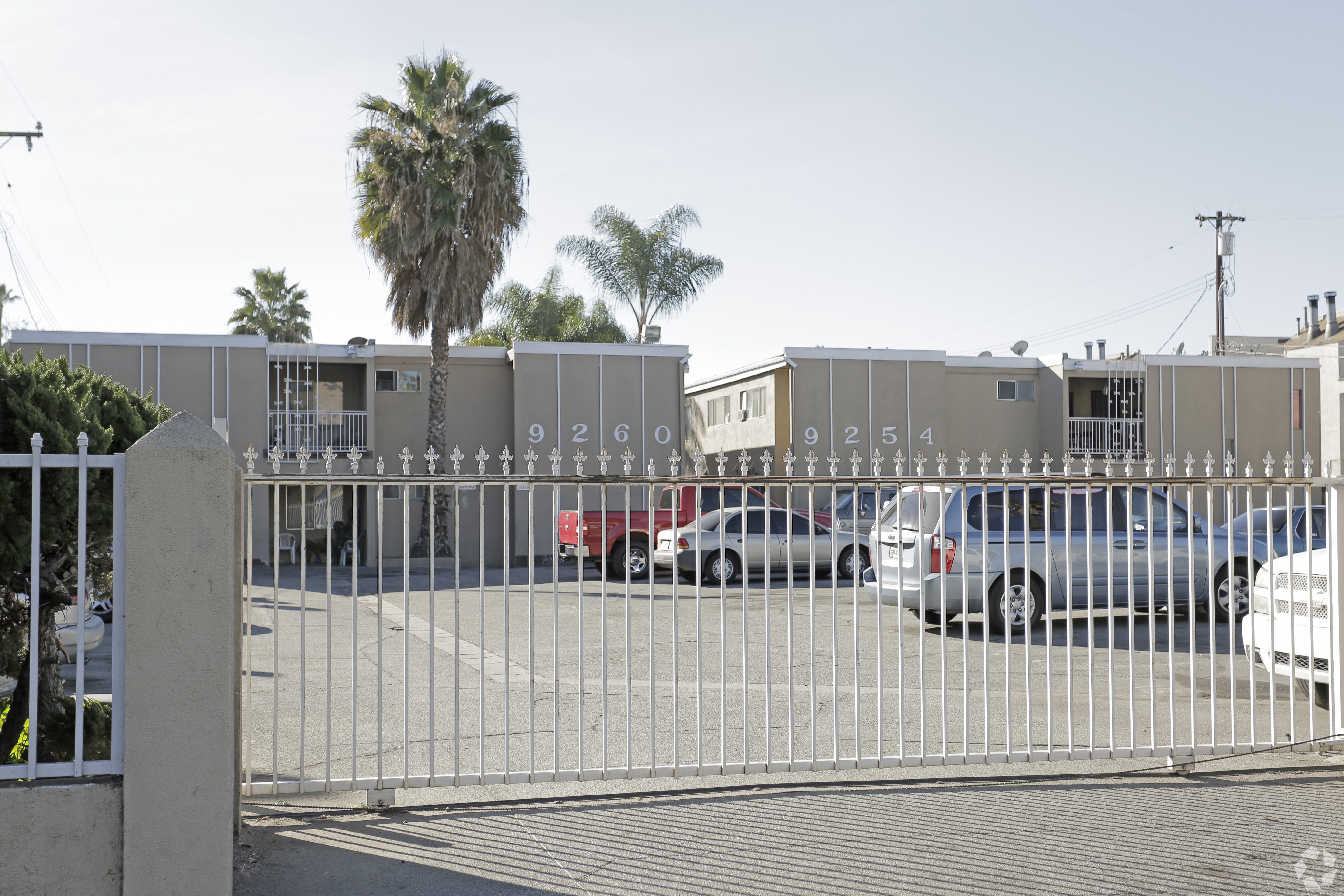 A gate with the numbers 92609254 on it blocks the view of a parking lot.